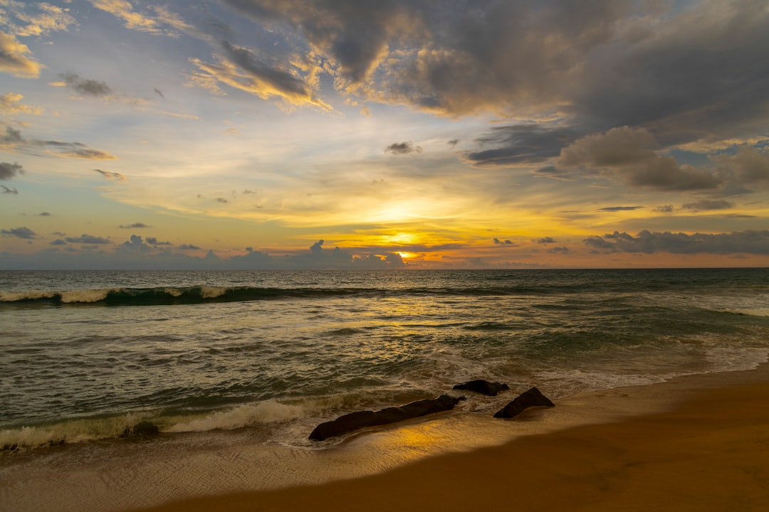 the sun is setting over the ocean on the beach