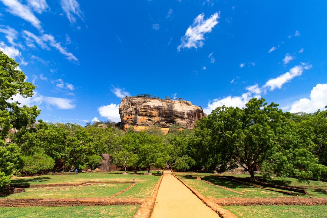 A path leading toward the Sigiriya rock fortress in Sri Lanka under a blue sky